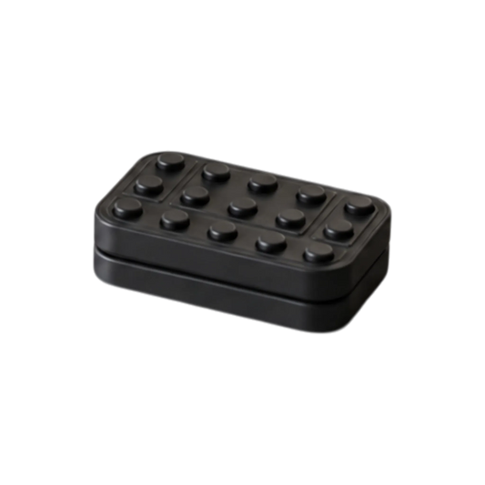 Angled view of the Brix magnetic fidget slider showing its raised studs and the seam between its plates.