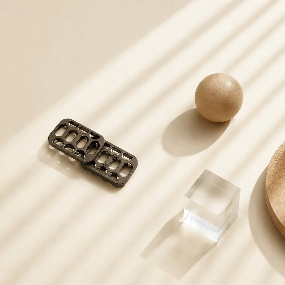 Arca magnetic fidget slider with offset plates beside a wooden sphere and a clear block.