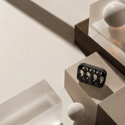 Arca open-frame fidget slider on a square block among geometric display objects.