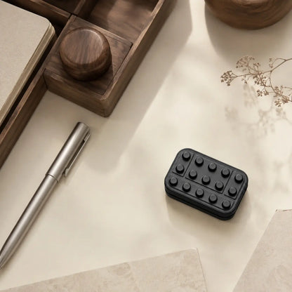 Overhead view of the Brix fidget slider on a desk beside a pen, wooden tray, and dried branch.