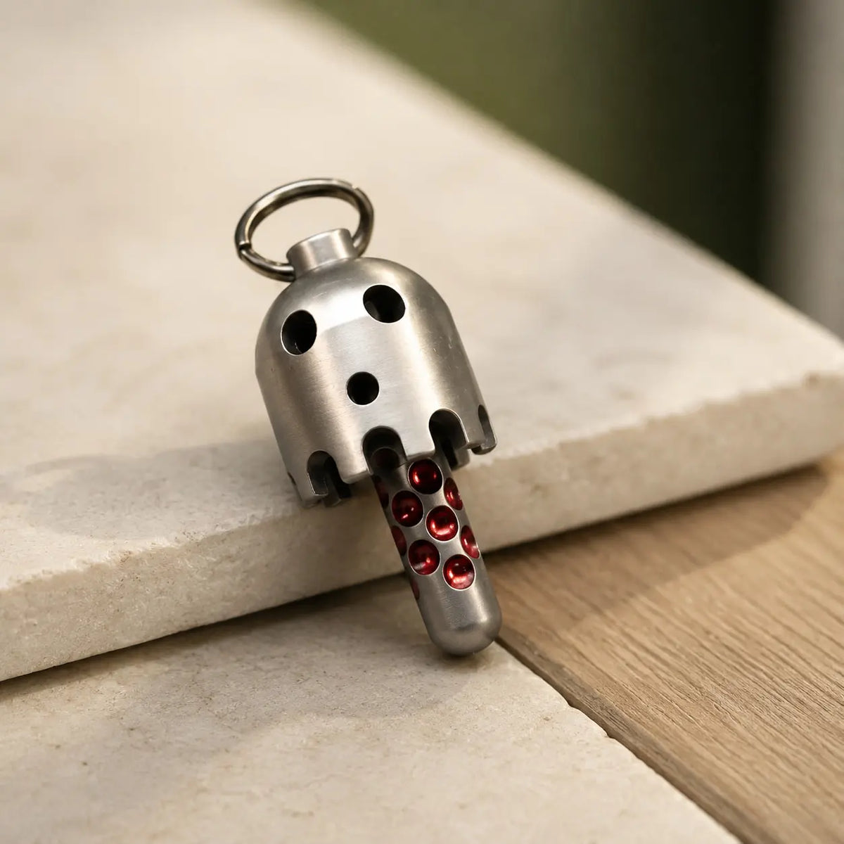 Daze bell pendant leaning against a pale ledge above a wooden surface.