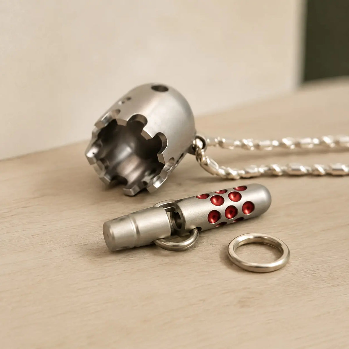 Daze bell pendant parts laid out on a wooden surface beside the chain.