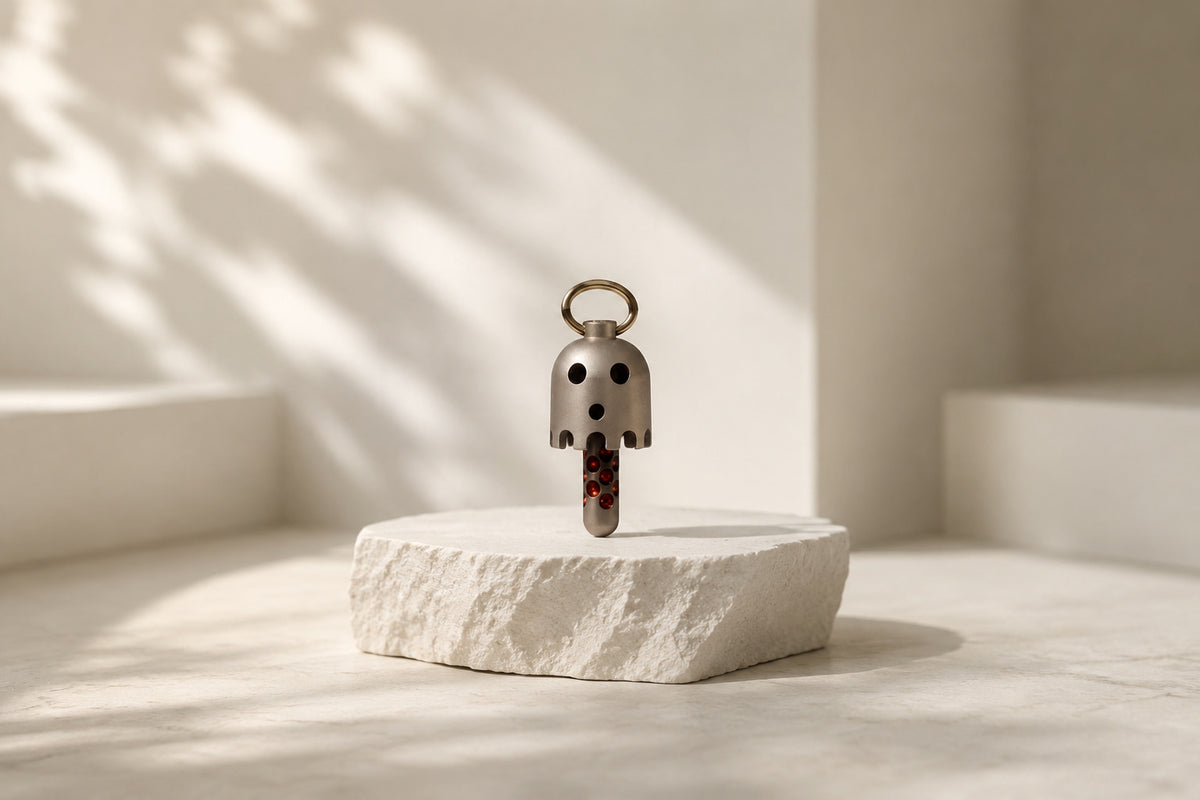Daze bell pendant standing on a round textured block in a softly lit setting.