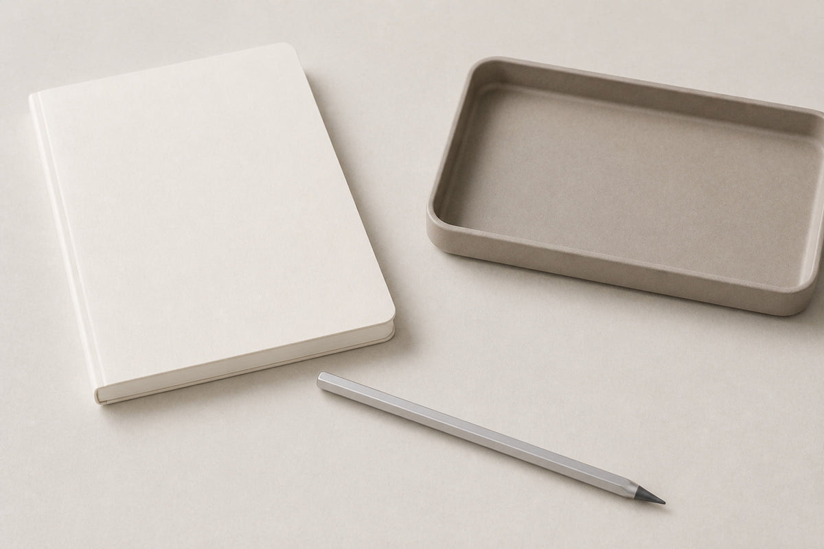 Facet pencil arranged with a closed notebook and a rectangular tray