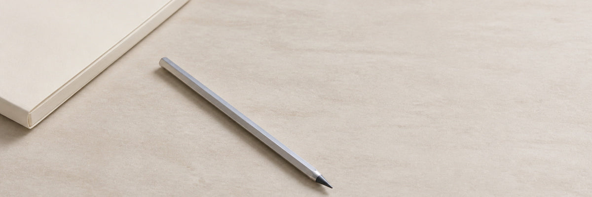 Facet pencil beside the corner of a notebook on a pale desk