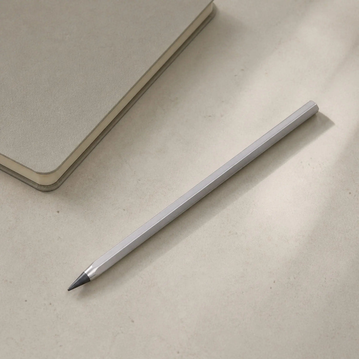 Facet pencil beside a closed notebook on a light desk