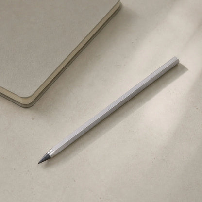 Facet pencil beside a closed notebook on a light desk