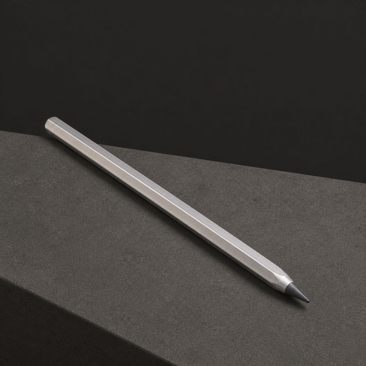 Facet pencil resting diagonally on a gray block against a dark background