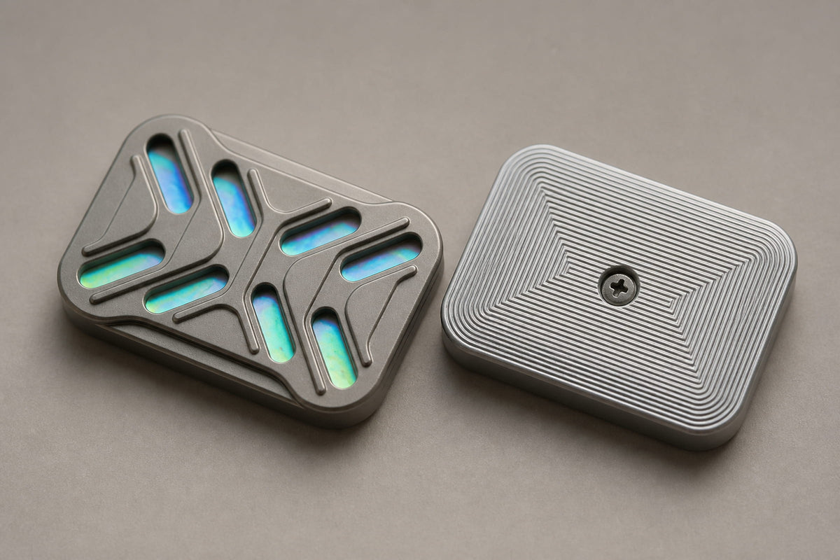 Gleam slider plates side by side on a gray surface, showing the iridescent face and grooved back.