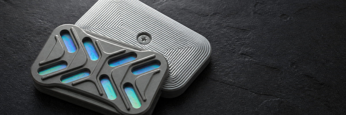 Gleam magnetic slider on a dark textured surface, with an iridescent face and grooved back plate.