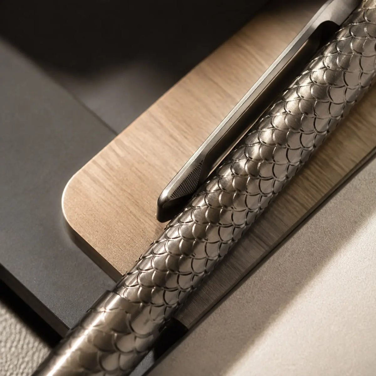 Close-up of Imbra’s fish-scale barrel and pocket clip beside a wooden surface