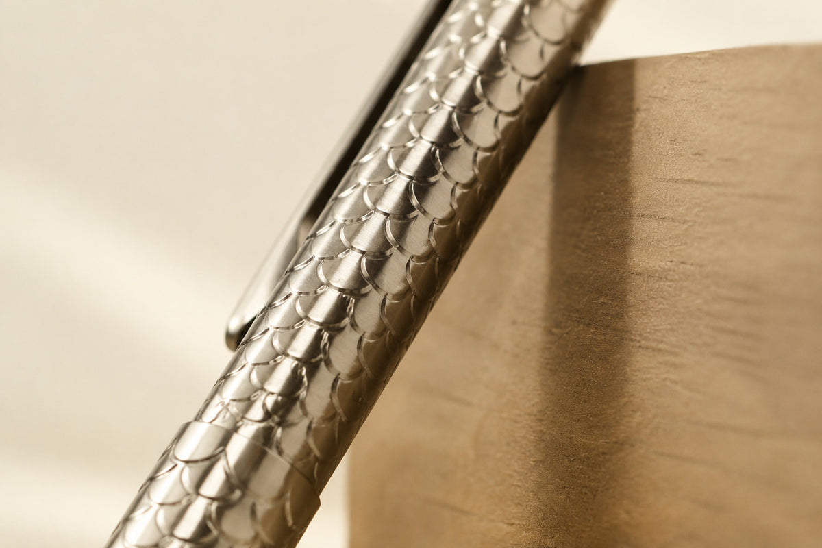 Close-up of Imbra’s overlapping scale pattern and pocket clip against a tan surface