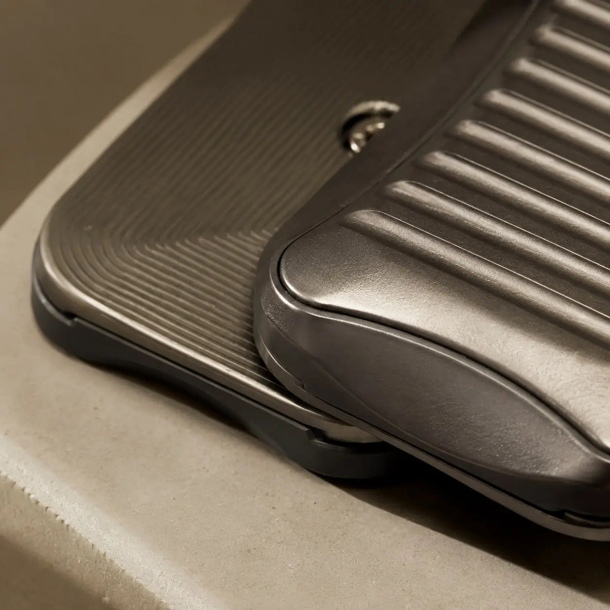 Close-up of the broad grooves and fine lines on the two offset plates of the Stria fidget slider.