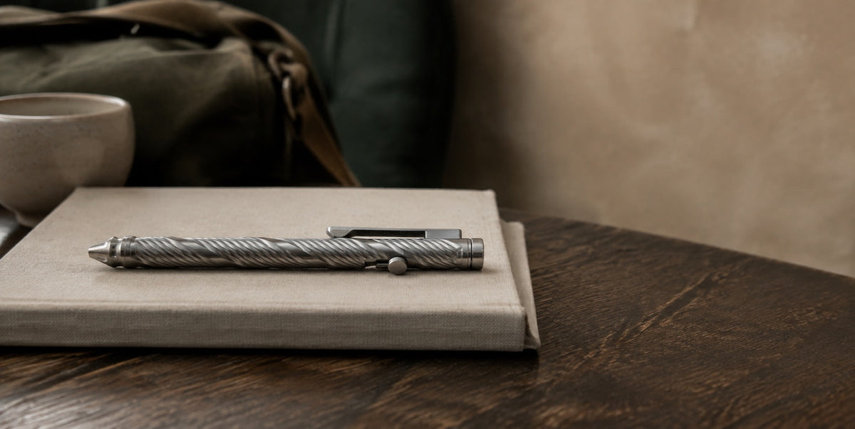 Whorl pen on a light-colored notebook with a cup and bag nearby